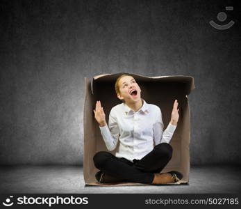 Limited possibilities. Young businesswoman sitting in carton box and feeling uncomfortable