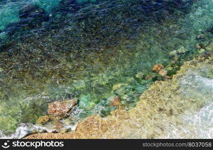 Limpid sea water surface with stones on bottom. View from above. Nature background.