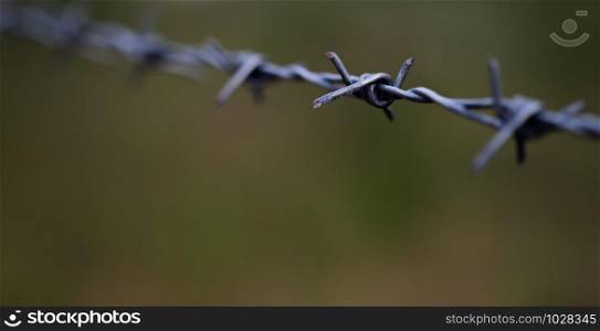Line of barbed wire with little dust and sweat with blurred background, selective focus.