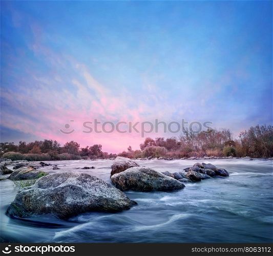 Line of stones stretching out into the water on pink dawn. Line of stones