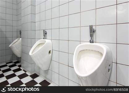 line of white urinals in public toilet