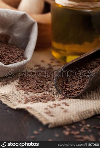 Linen bag of raw natural organic linseed flax-seed with spoon and oil on wood background. Healthy omega 3 product.Macro