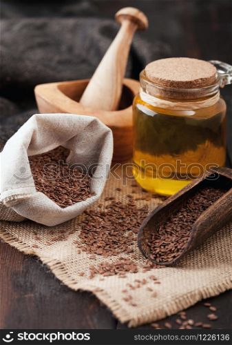 Linen bag of raw natural organic linseed flax-seed with spoon and oil on wood background. Healthy omega 3 product.