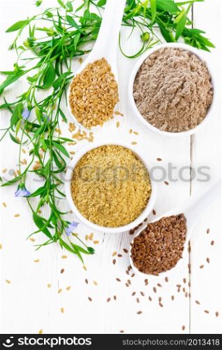 Linen bran and flour in two white bowls, seeds in spoons, flax leaves and flowers on the background of a wooden board from above