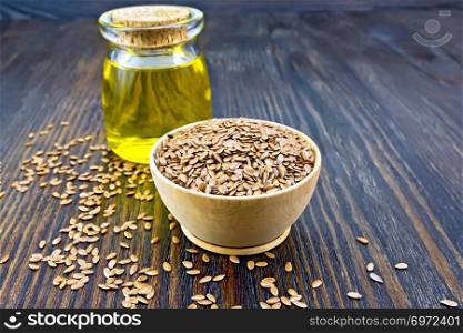 Linen brown seeds in a bowl, linseed oil in a glass jar on a wooden board background