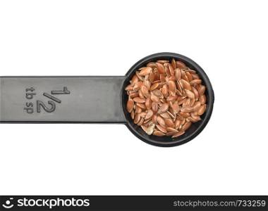 Linseed in measuring spoon on white background