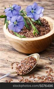 Linseed on wooden background. Flax seed and flowering buds of flax on a wooden background