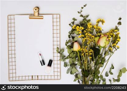 lipstick nail varnish paper golden metallic clipboard with flower bouquet isolated white background