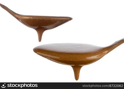 Liquid Chocolate dripping from two spoons on white background.