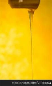 Liquid stream of sweet amber flower honey flows. Liquid and viscous stream of honey. Stream of honey flows from a wooden honey spoon