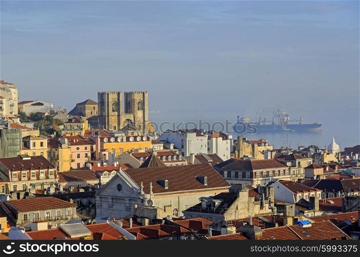 Lisbon cathedral, city roofs and bulk-carrier ship in the sea