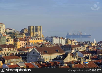 Lisbon cathedral, city roofs and bulk-carrier ship in the sea