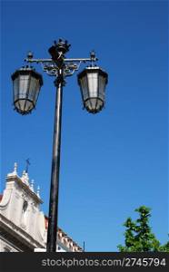 Lisbon scene with vintage lamp posts against blue sky background