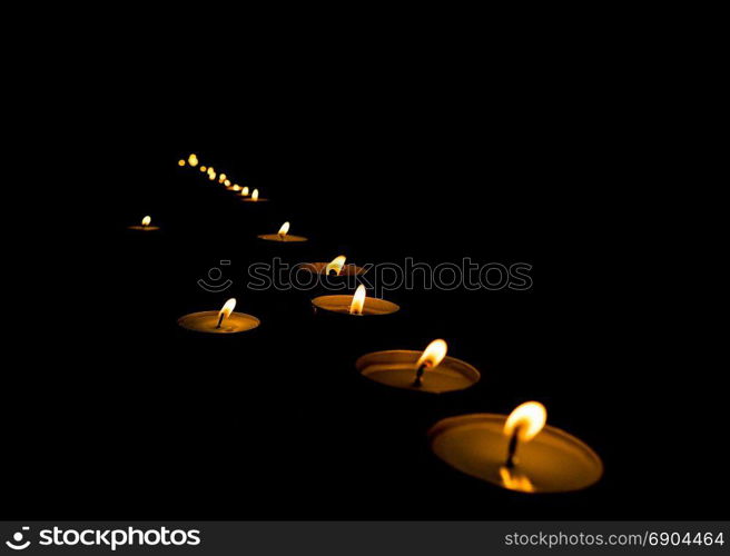 lit candles in the dark. flickering flame of lit votive prayer wax candles in a church shining in the dark