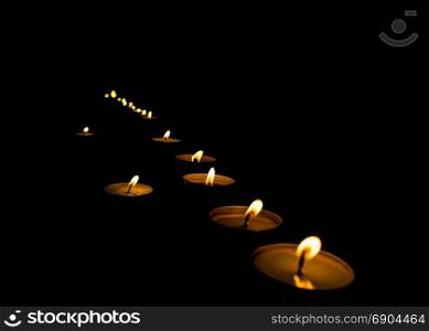lit candles in the dark. flickering flame of lit votive prayer wax candles in a church shining in the dark