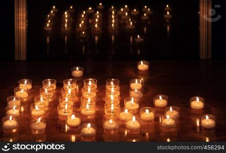 Lit candles on a table next to a window in the dark. Candles on a table next to a window