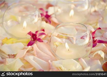 Lit candles with purple orchids and rose petals.