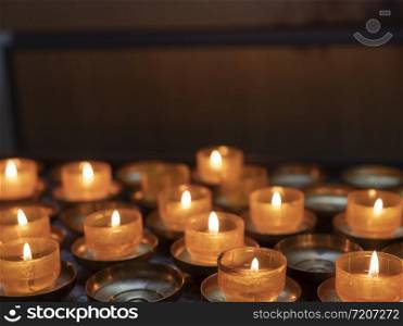 lit tea light candles and orange candle holders in catholic church