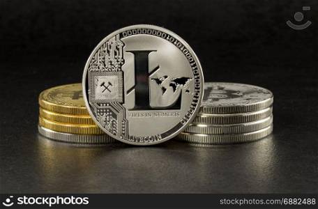 litecoin and bitcoin with black background with a single litecoin facing the camera in sharp focus with shading on the icon letter B on the face of the bit coin
