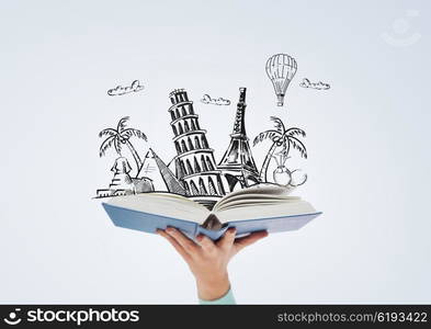 literature, travel and education concept - close up of woman hand holding open blue book with doodles