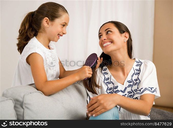 Litle girl helping mother brushing her hair