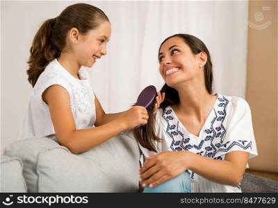 Litle girl helping mother brushing her hair