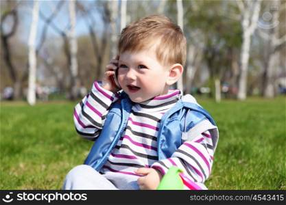 litlle boy holding mobile phone in the park