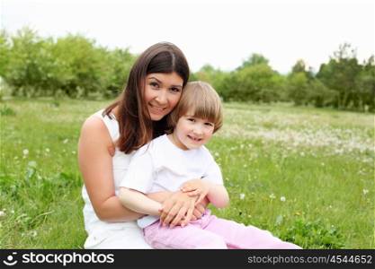litlle girl with her mother outdoors on the grass