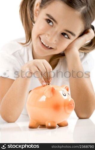 Litt≤girl lying on floor and inserting a o≠€coin on theπggy-bank