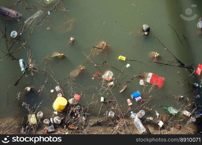 Littered, fouled, dirty surface of water with household waste - plastic bottles, tetropacks, polyethylene and plastic cups, which could be recycled.