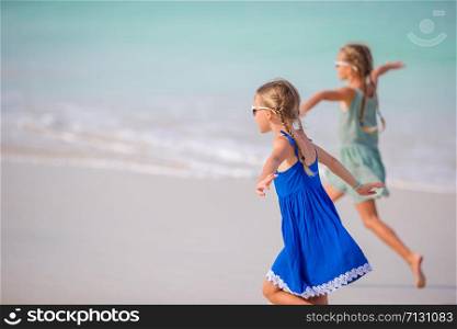Little adorable and happy girls running on the beach on summer vacation. Little girls having fun enjoying vacation on tropical beach