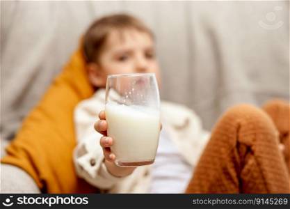 Little adorable boy sitting on the couch at home and drinking milk. Fresh milk in glass, dairy healthy drink. Healthcare, source of calcium, lactose. Preschool child with casual clothing. Little adorable boy sitting on the couch at home and drinking milk. Fresh milk in glass, dairy healthy drink. Healthcare, source of calcium, lactose. Preschool child with casual clothing.