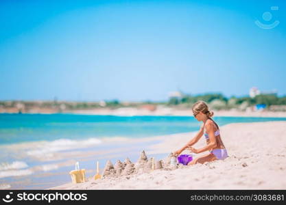 Little adorable girl at tropical beach making sand castle. Little girl at tropical white beach making sand castle