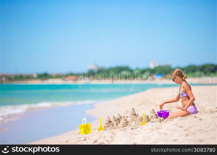 Little adorable girl at tropical beach making sand castle. Little girl at tropical white beach making sand castle