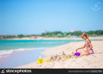 Little adorable girl at tropical beach making sand castle. Little girl at tropical white beach making sand castle