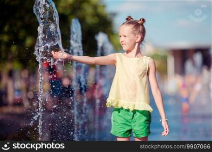 Little adorable girl having fun in street fountain at hot sunny summer day. Little adorable girl have fun in street fountain at hot sunny day