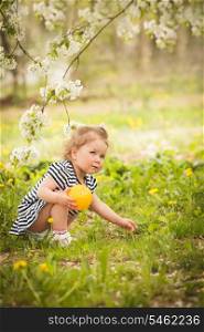 Little adorable girl in the garden, plays with ball