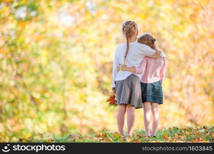 Little adorable girl outdoors on a warm autumn day. Back view of kids in fall background autumn trees. Little adorable girls at warm day in autumn park outdoors