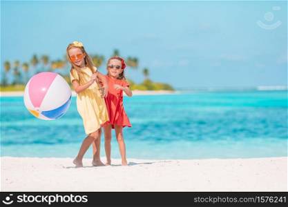 Little adorable girls playing on beach with ball. Little adorable girls playing with air ball on the beach. Kids having fun on the seashore