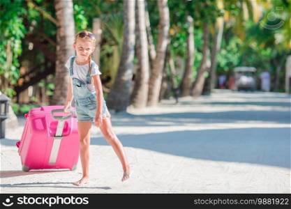 Little adorable girls with big luggage in hands on the vacation. Little adorable girl with big suitcase on tropical white beach