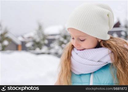Little adorable happy girl in the snow winter day outdoors. Portrait of little adorable girl in snow sunny winter day