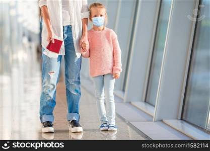 Little adorable kid with surgical mask face protection at international airport. Mother and little daughter with boarding pass at airport terminal ready for vacation. Little kid in airport waiting for boarding