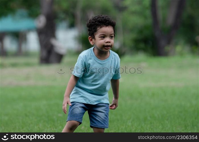 Little African American kid boy enjoy playing and running the park. Active child having fun with outdoor activity in summer