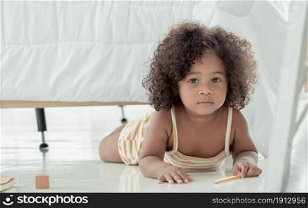 Little african black girl with afro hair playing toys in bedroom at home