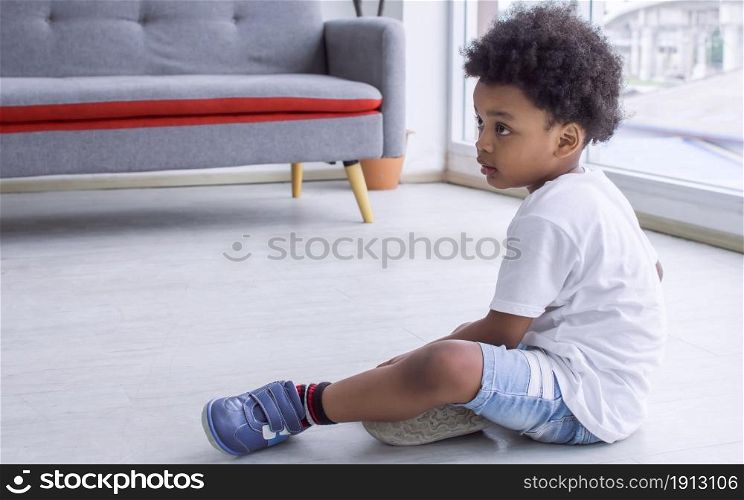 Little african cute boy sitting on the floor in living room at home. Education and Lifestyle Concept.