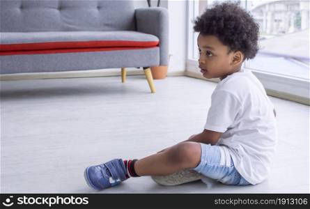Little african cute boy sitting on the floor in living room at home. Education and Lifestyle Concept.