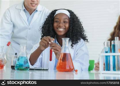 Little African kids learning chemistry in school laboratory. Teacher man teaching clever little girl doing a chemical science experiment in a laboratory on white background