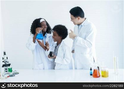 Little African kids studying chemistry and doing chemical science experiment in laboratory at school. Happy dark skinned girl showing test bottle to Asian teacher man and he thumbs up