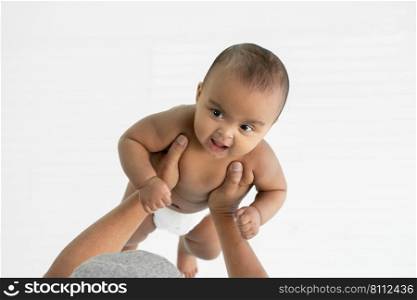 Little African newborn girl wear diaper smiling and enjoy with senior father lifting her up in the air. Love and close relationship in family concept. White background