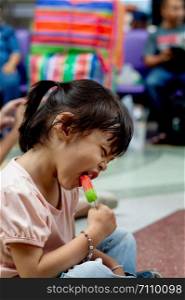 Little asian child girl eating ice cream.